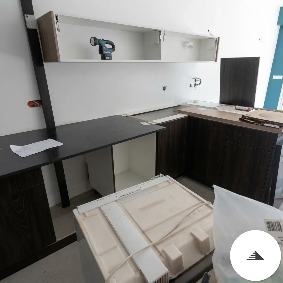 Cuisines sur mesure — Phase de montage, plan de travail noir partiellement posé et caissons hauts en attente de finition à Bastia | Gonzalez Agencement