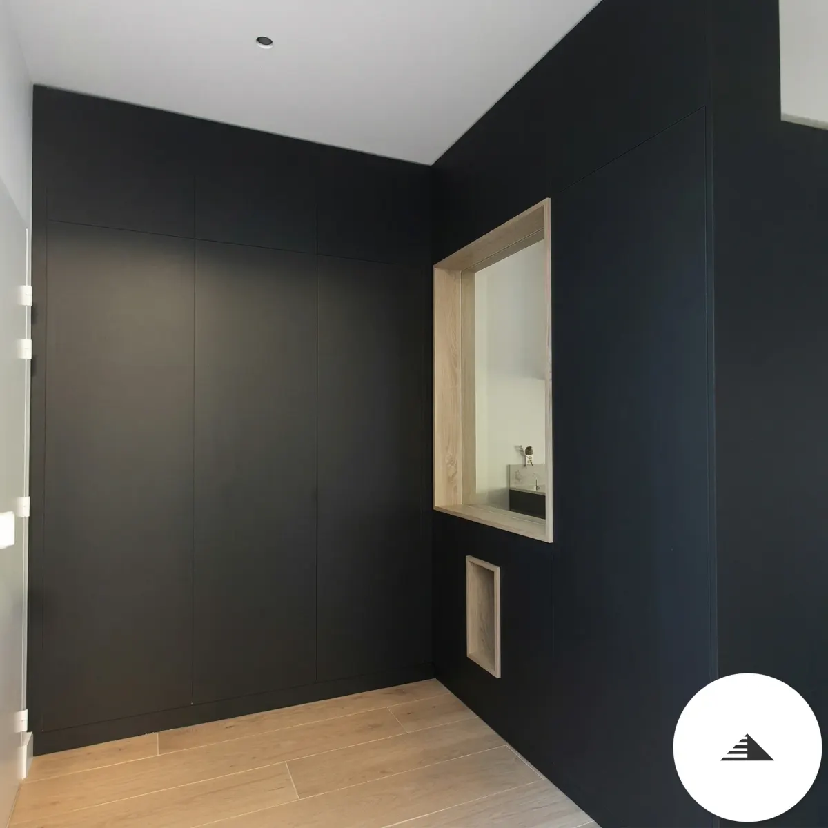 Cuisines sur mesure — Vue frontale des placards noirs fermés avec niche bois lumineuse intégrée et rangements bas, résultat final à Bastia | Gonzalez Agencement