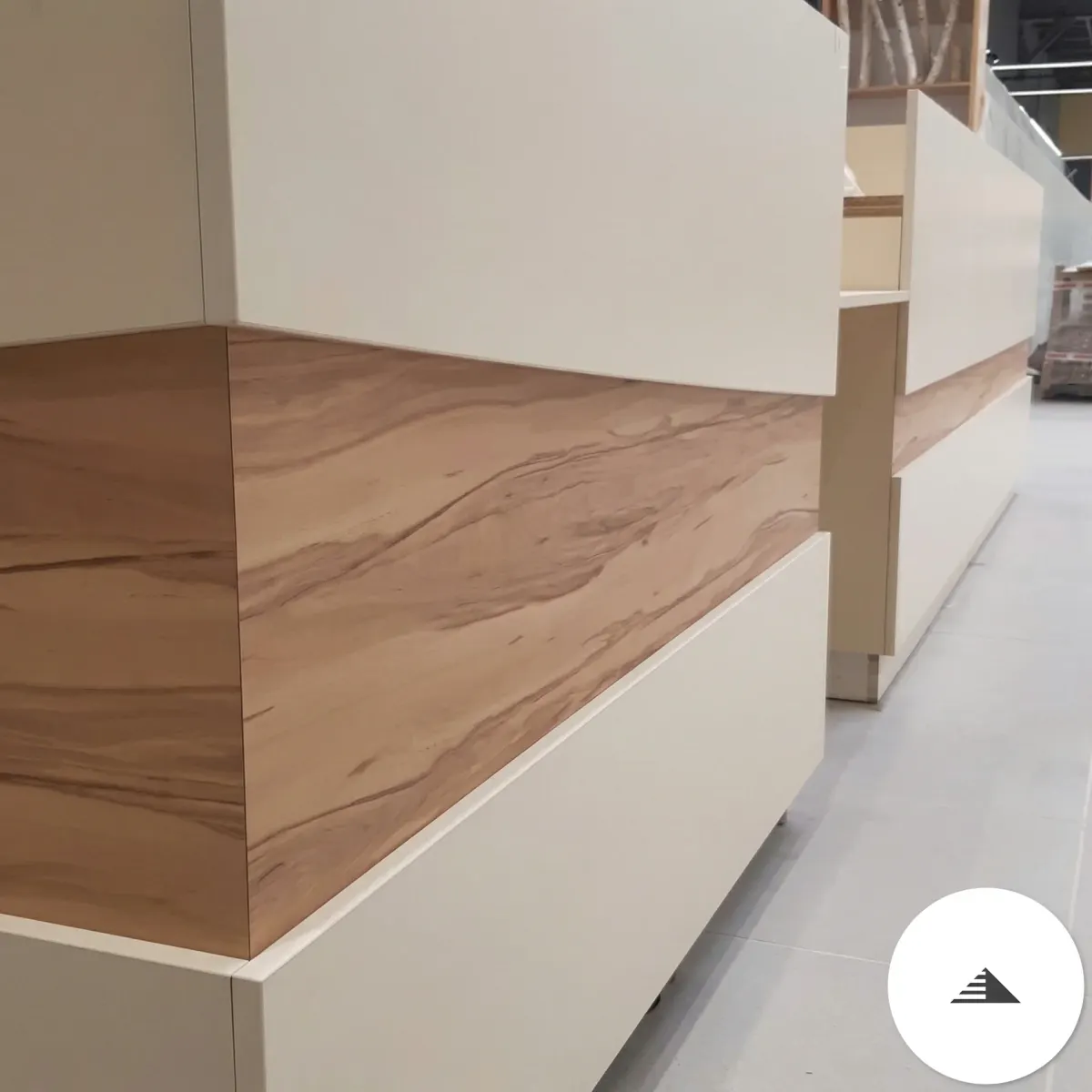 Meubles sur mesure — Vue latérale d'une longue banquette beige laqué et bois veiné warm en cours d'installation dans la galerie commerciale à Le Pian Médoc | Gonzalez Agencement