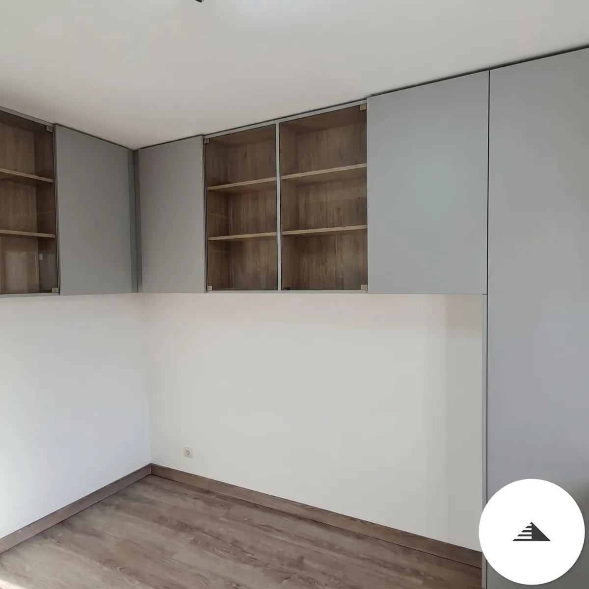 Aménagements sur mesure — Armoires hautes gris-bleu laqué mat en angle avec portes vitrées translucides révélant les étagères, parquet gris, vue de la pièce à Bordeaux | Gonzalez Agencement