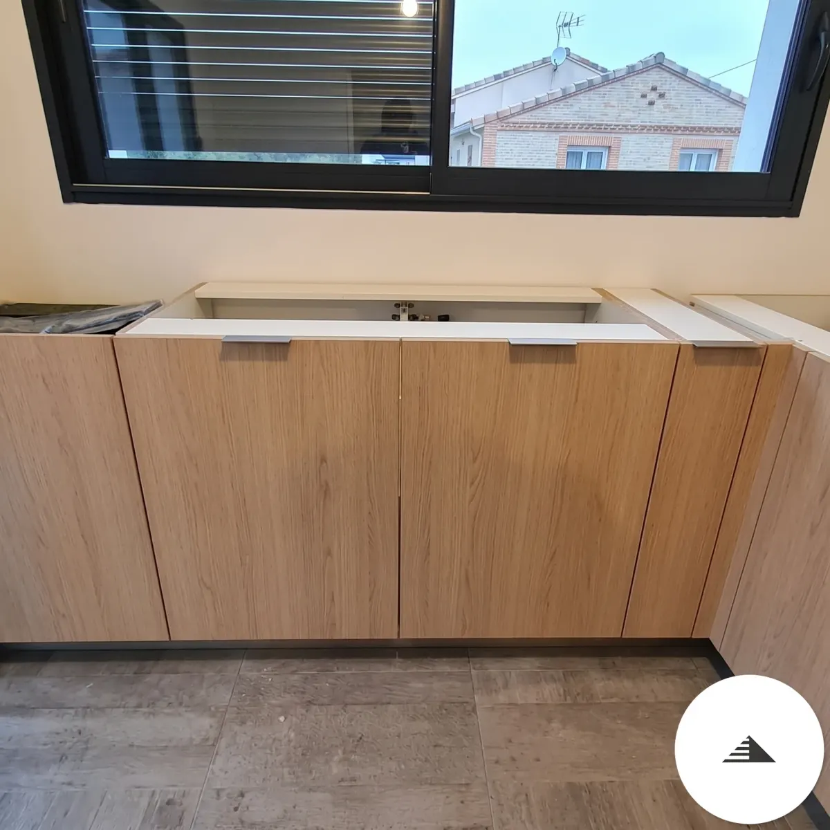 Cuisines sur mesure — Caissons bas en bois naturel teinte érable avec poignées aluminium intégrées et plan de travail en cours de pose, vue de face à Toulouse | Gonzalez Agencement