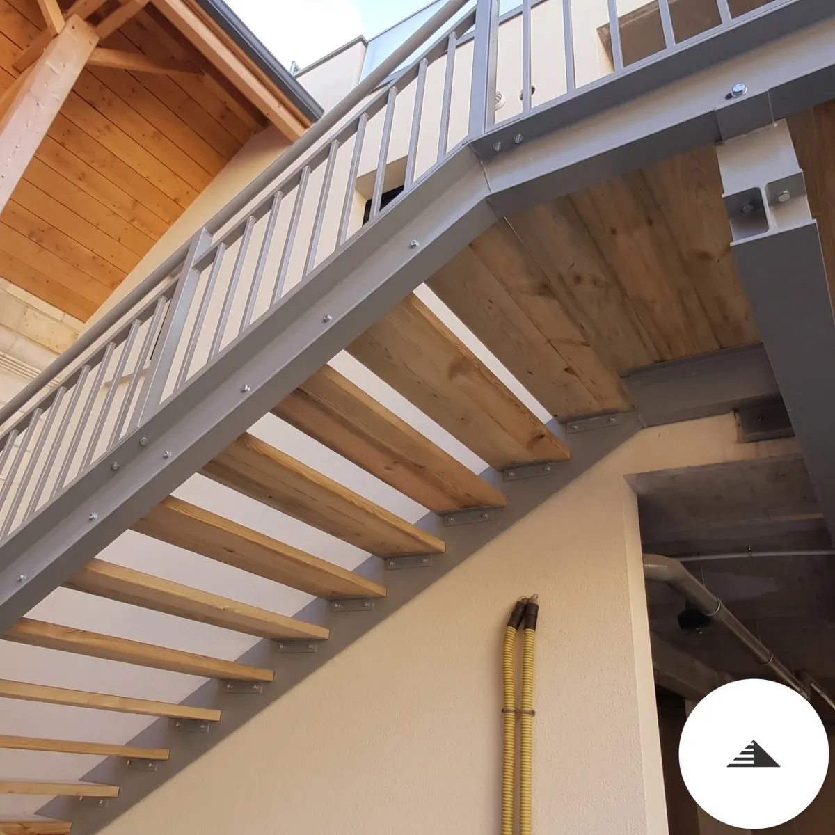 Escaliers sur mesure — Vue de dessous de l'escalier extérieur, structure acier grise et dessous des marches bois clair, vue en contre-plongée à Bordeaux | Gonzalez Agencement