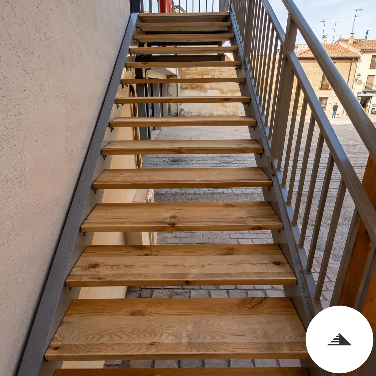 Escaliers sur mesure — Vue de face en descente, marches pin massif sur limons acier gris, garde-corps métal avec main courante ronde, fond pierre à Bordeaux | Gonzalez Agencement