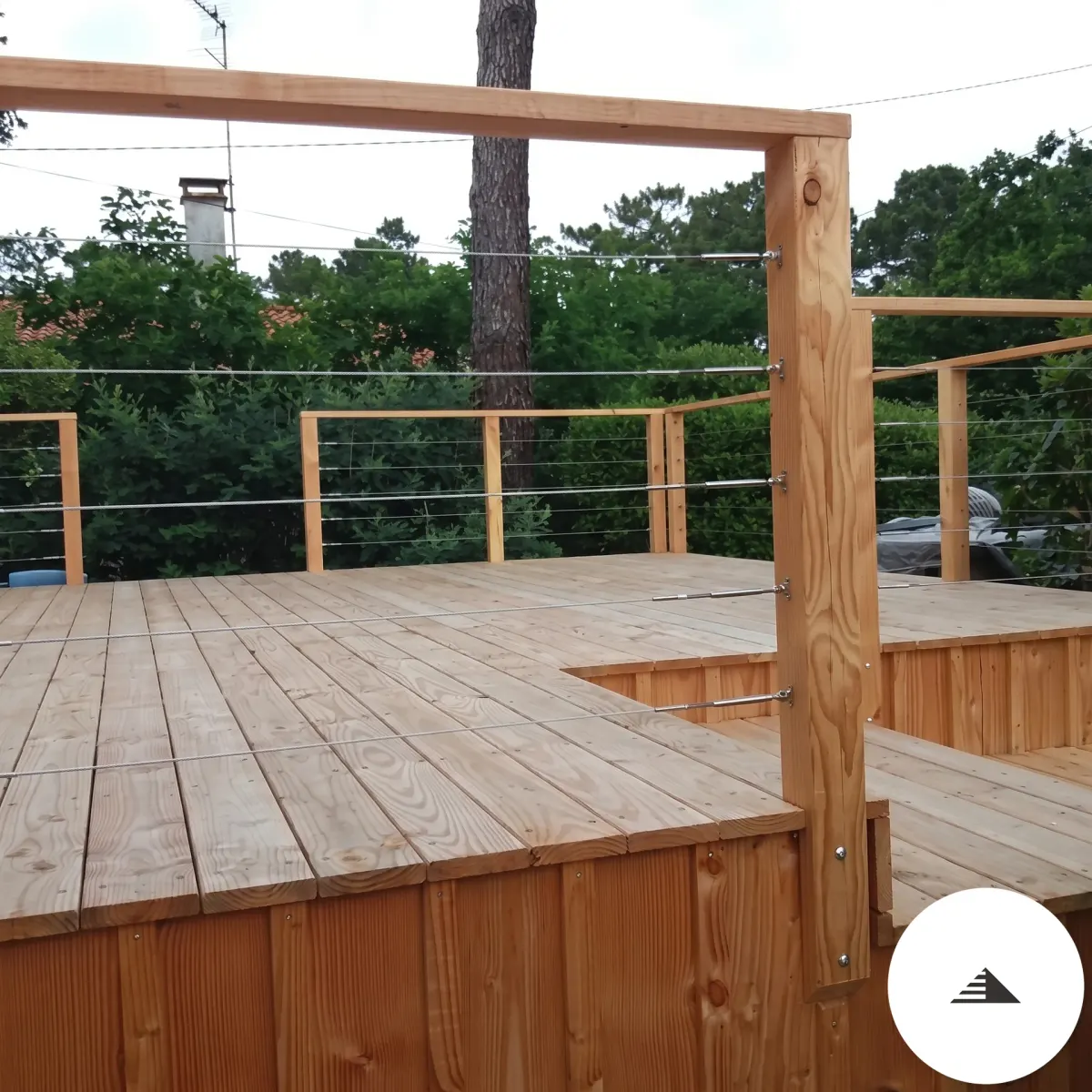 Terrasses sur mesure — Vue de face de la terrasse bois clair, garde-corps câbles inox et banc en bois intégré dans le garde-corps, cadre de pergola visible à Bordeaux | Gonzalez Agencement