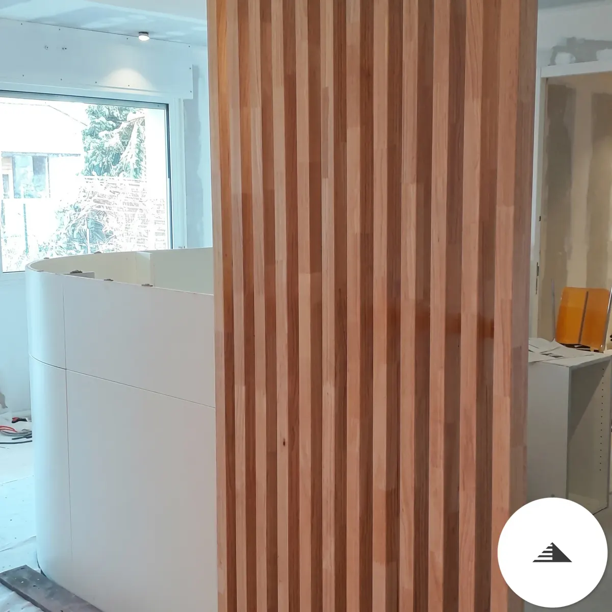Agencement sur mesure — Claustra en tasseaux bois clair vu de face dans un espace lumineux, comptoir blanc et mobilier en arrière-plan à Bordeaux | Gonzalez Agencement