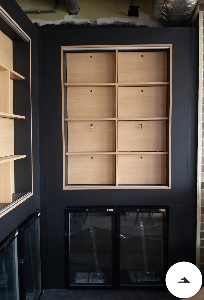 Meubles sur mesure — Détail d'un module de bibliothèque en cases bois clair sur fond noir mat, vitrine réfrigérée intégrée en partie basse à Bordeaux | Gonzalez Agencement
