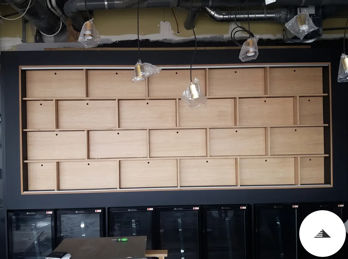 Meubles sur mesure — Panneau principal du présentoir mural en cases bois clair asymétriques encadrées de noir mat, vue de face à Bordeaux | Gonzalez Agencement