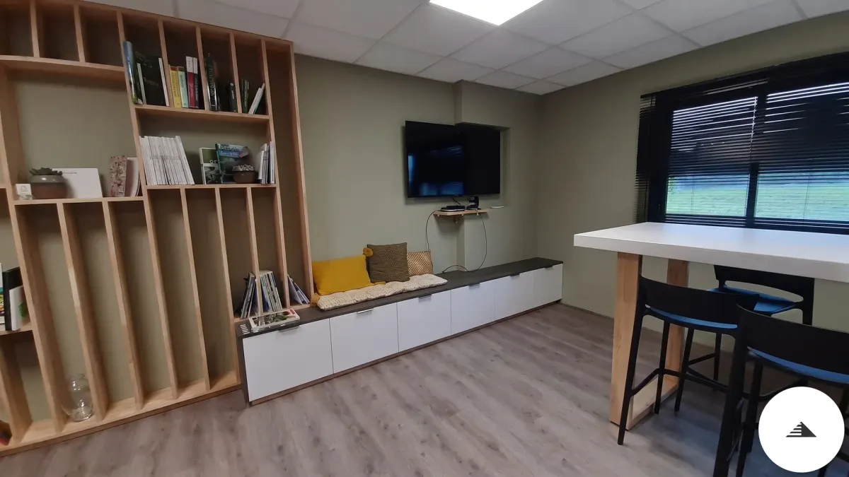 Agencement sur mesure — Bibliothèque bois naturel ouverte et banquette avec meuble bas laqué blanc, vue côté TV murale dans le co-working à Bordeaux | Gonzalez Agencement