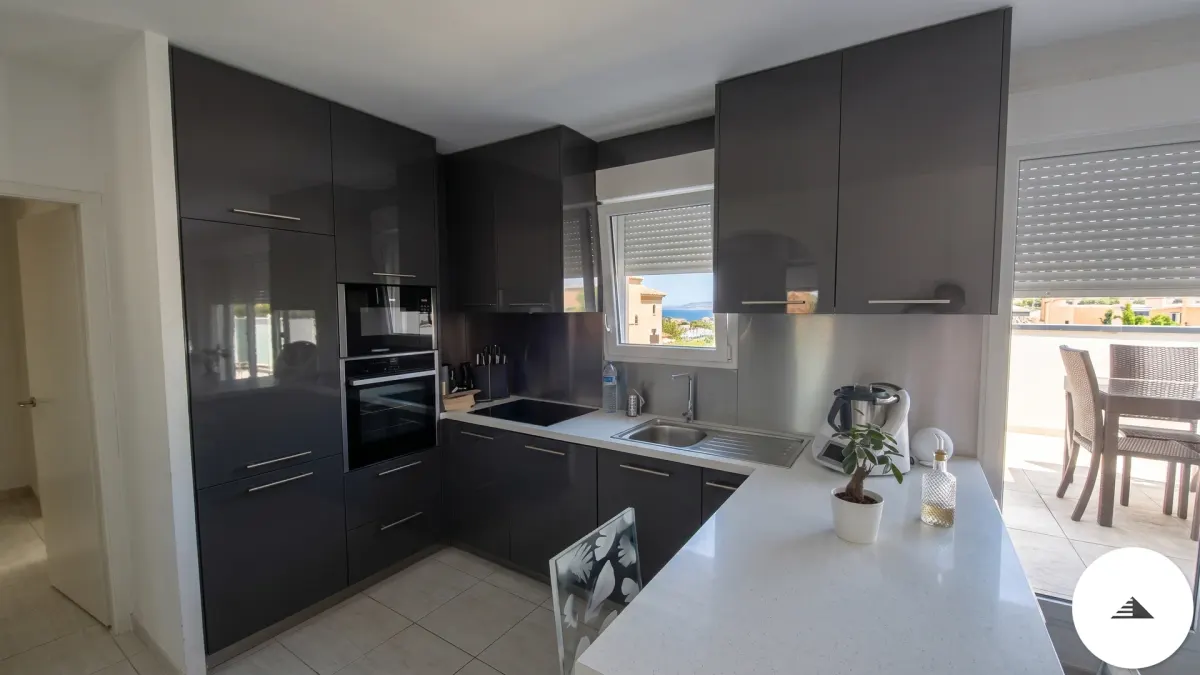 Cuisines sur mesure — Vue large d'une cuisine en U laquée gris anthracite brillant avec colonne haute fours intégrés et plan de travail blanc à Bordeaux | Gonzalez Agencement